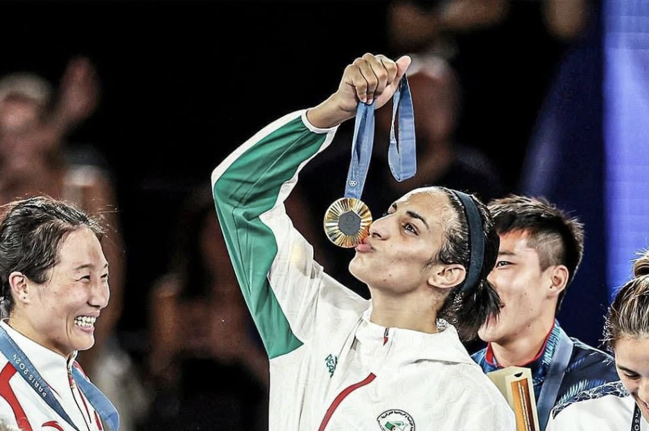 A imagem é uma fotografia que captura um momento de celebração. A iluminação é brilhante, permitindo que os detalhes da roupa e da expressão da mulher sejam destacados. A composição da imagem demonstra a satisfação e o orgulho da mulher que conquista a medalha.