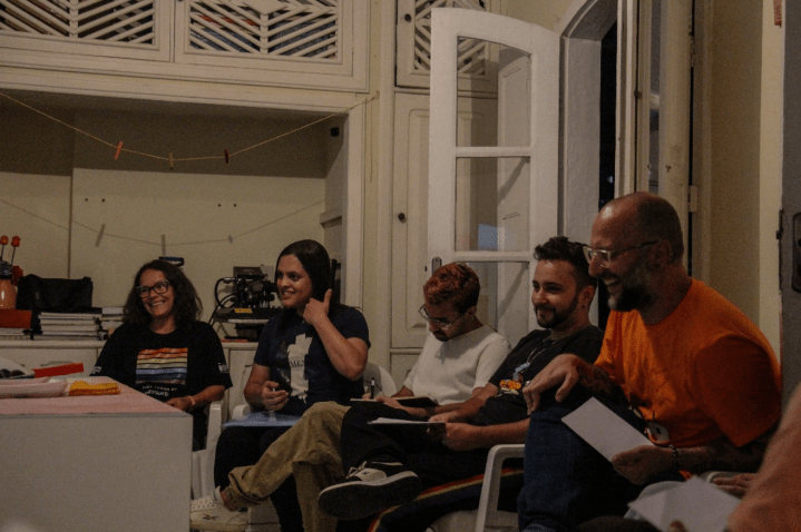 Cinco pessoas sorridentes reunidas em uma sala. 