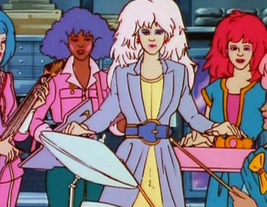 Imagem de desenho animado de cinco mulheres com cabelos estilo anos 80 em cores chamativas rosa, azul, lilás, vermelho e pink. Elas tocam instrumentos de rock.