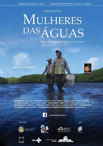 Fotografia em plano aberto que retrata o trabalho exaustivo das marisqueiras no manguezal. A imagem mostra mulheres curvadas sobre a lama ou na água rasa, possivelmente com cestos ou baldes, em meio à densa vegetação e raízes aéreas do mangue. O registro ilustra a profunda interdependência entre essas mulheres e o ecossistema, o "corpo-território" ameaçado pela crise dos plásticos e a poluição.
